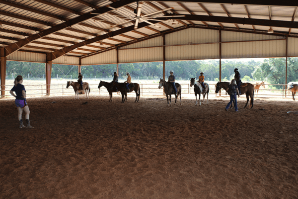 campers riding horses in arena