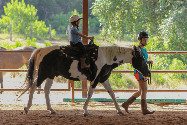camper riding horse with staff leading