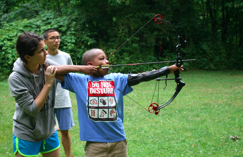 counselor teaching archery to camper